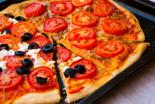 Pieces of homemade pizza with tomates and olives.