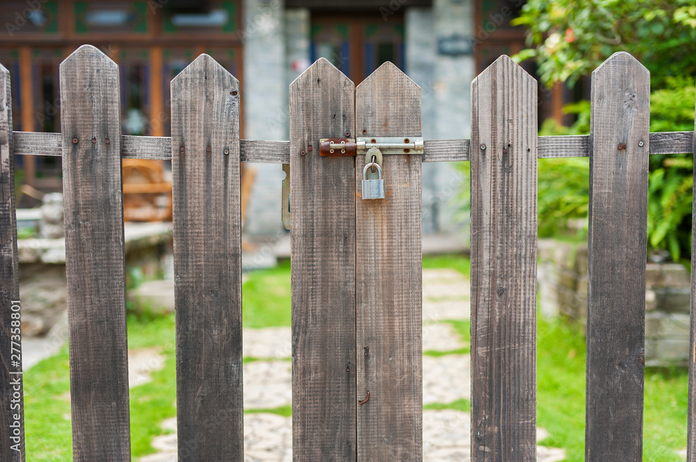 A closed gate of wooden fence of backyard garden