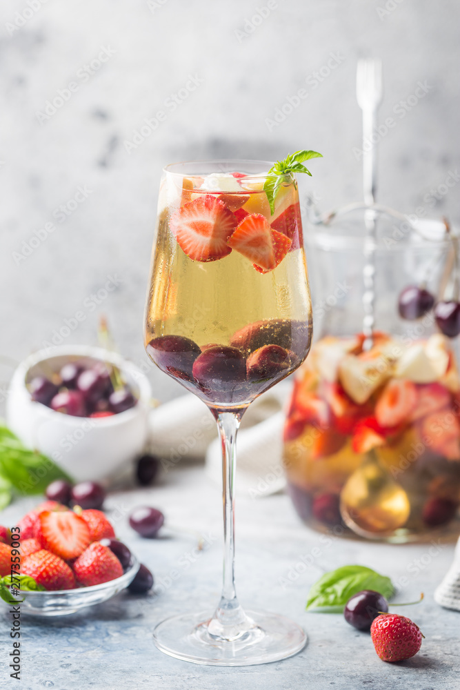 White wine sangria or punch with berries and ice in glass and pincher. Homemade refreshing fruit sangria. White wine sangria or punch with berries and ice in glass and pincher. Homemade refreshing fruit sangria.