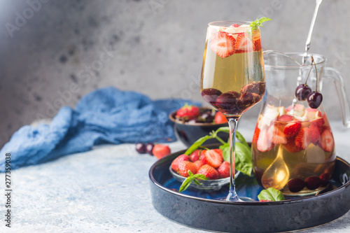 White wine sangria or punch with berries and ice in glass and pincher. Homemade refreshing fruit sangria.