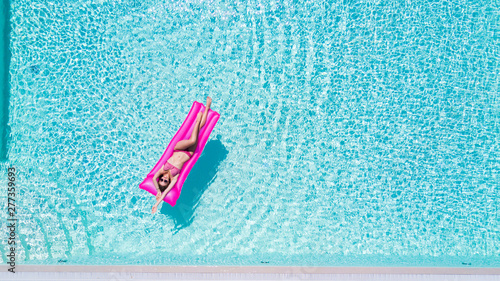 Young pretty woman floating on air mattress in swimming pool
