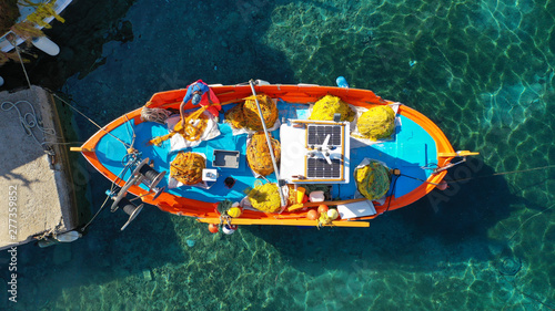 Aerial drone top view photo of traditional colourful fishing boat near iconic beach of Ornos with emerald clear sea  Mykonos island  Cyclades  Greece