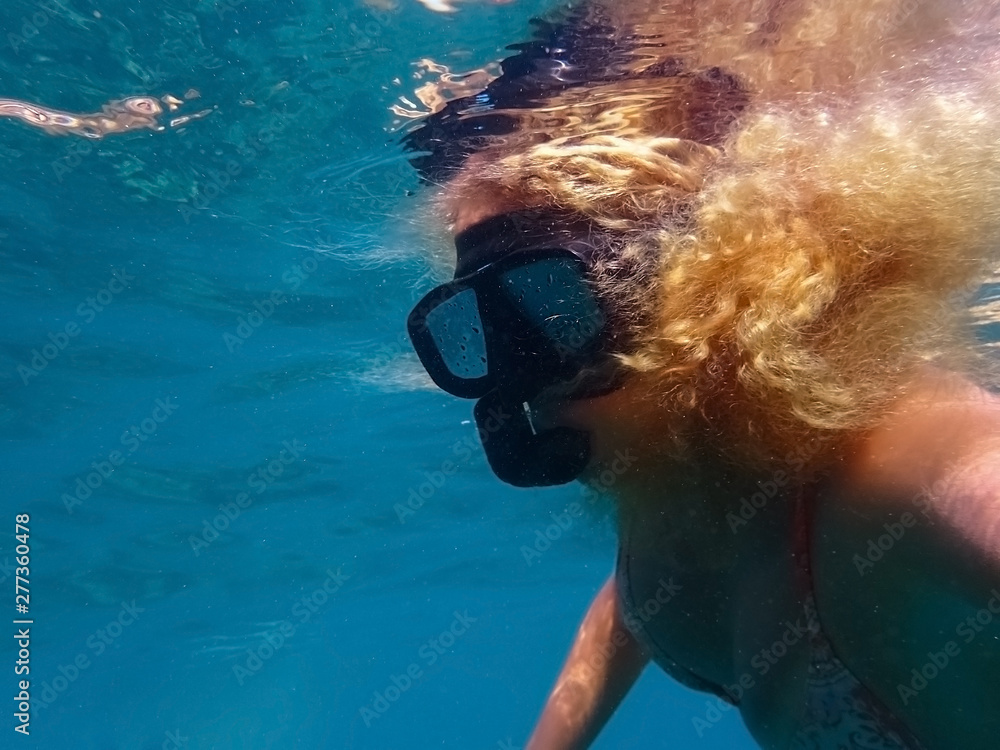 Blonde woman snorkelling in mask underwater