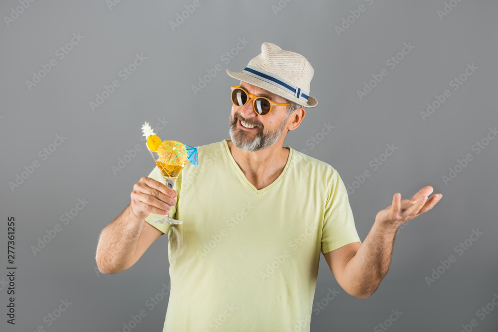 portrait of middle aged man summer dressed drinking cocktail on gray background