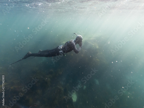 Freediving man in wetsuit exploring the wild underwater coast of Pembrokeshire whilst on a snorkeling beach holiday