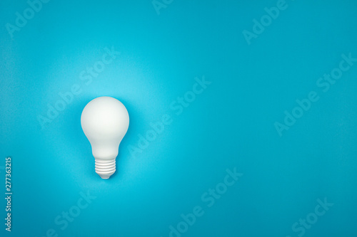white light bulb is shine on blue table. - business growth and great ideas concept.