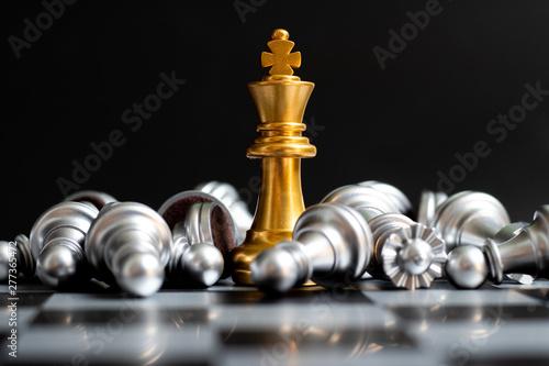 Obraz na plátne Gold king chess piece win over lying down silver pawn on black background