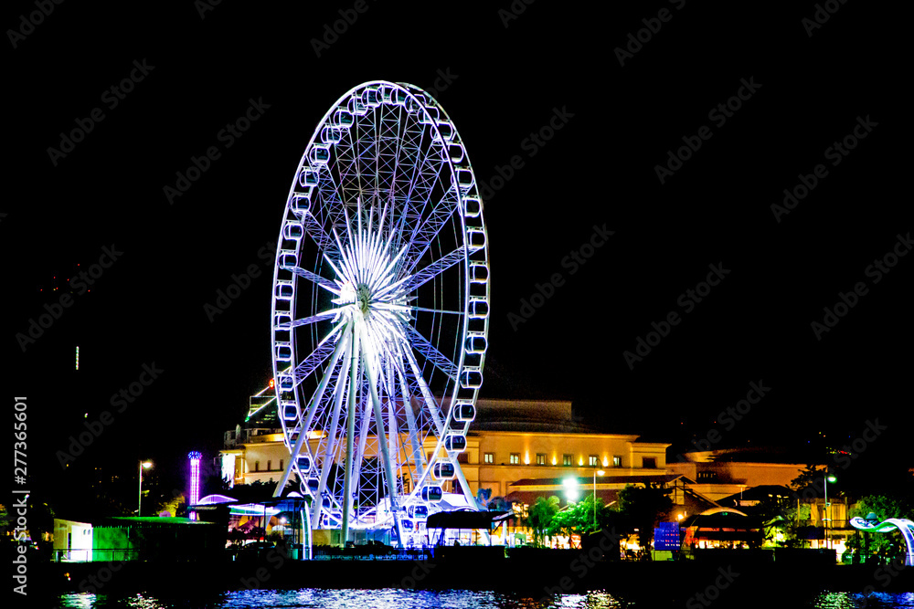 Ferris wheel, colorful lights at night.
