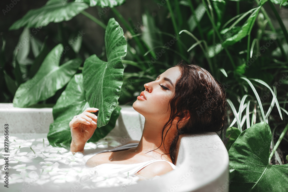Woman relaxing in round outdoor bath with tropical flowers, organic skin care, luxury spa hotel, lifestyle photo - obrazy, fototapety, plakaty 