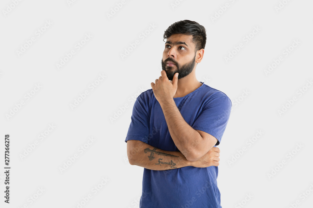 Beautiful male half-length portrait isolated on white studio background. Young emotional hindu man in blue shirt. Facial expression, human emotions, advertising concept. Thinking or choosing. Beautiful male half-length portrait isolated on white studio background. Young emotional hindu man in blue shirt. Facial expression, human emotions, advertising concept. Thinking or choosing.