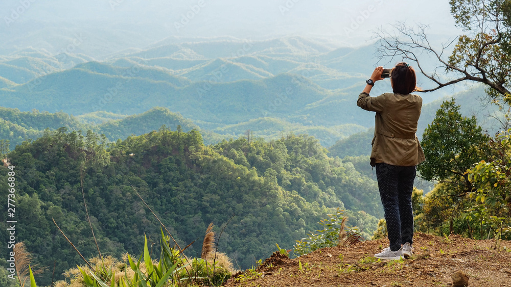A Woman Tourist Is Taking Photo of Mountains and Hills with Her Mobile Phone / Smart Phone at The Scenic View Point of Mae Hong Son Province, Northern Thailand.