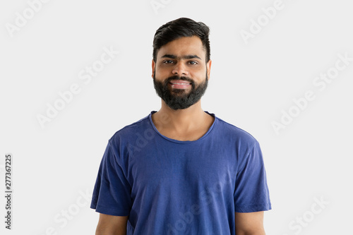 Beautiful male half-length portrait isolated on white studio background. Young emotional hindu man in blue shirt. Facial expression, human emotions, advertising concept. Standing and smiling.