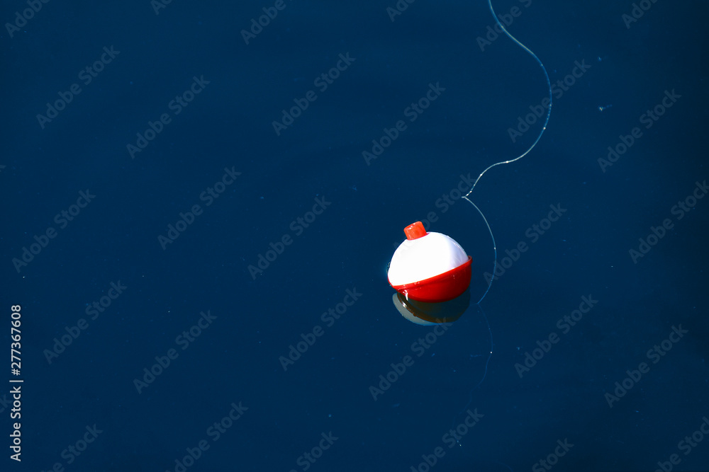 red and white floating fishing bobber with white fish line on dark blue water - obrazy, fototapety, plakaty 