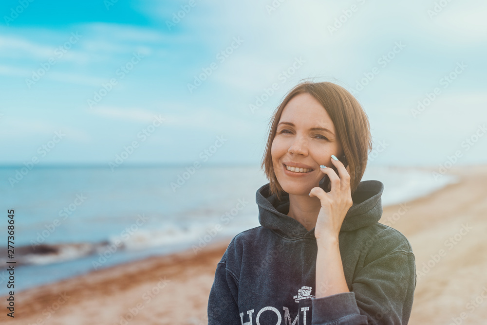 The woman smiles and communicates by phone on the seashore, the ocean. The woman smiles and communicates by phone on the seashore, the ocean.