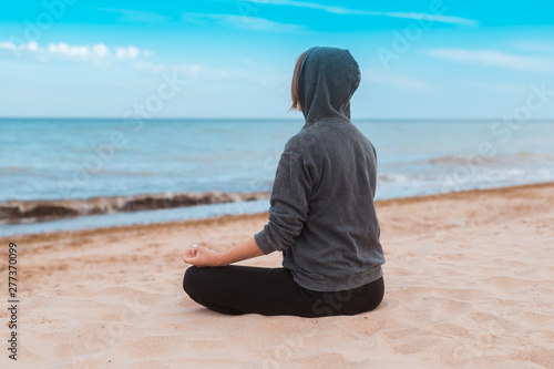 Woman practicing meditation on the seashore, ocean. Practice clearing thoughts, calming down. Yoga on the coast.