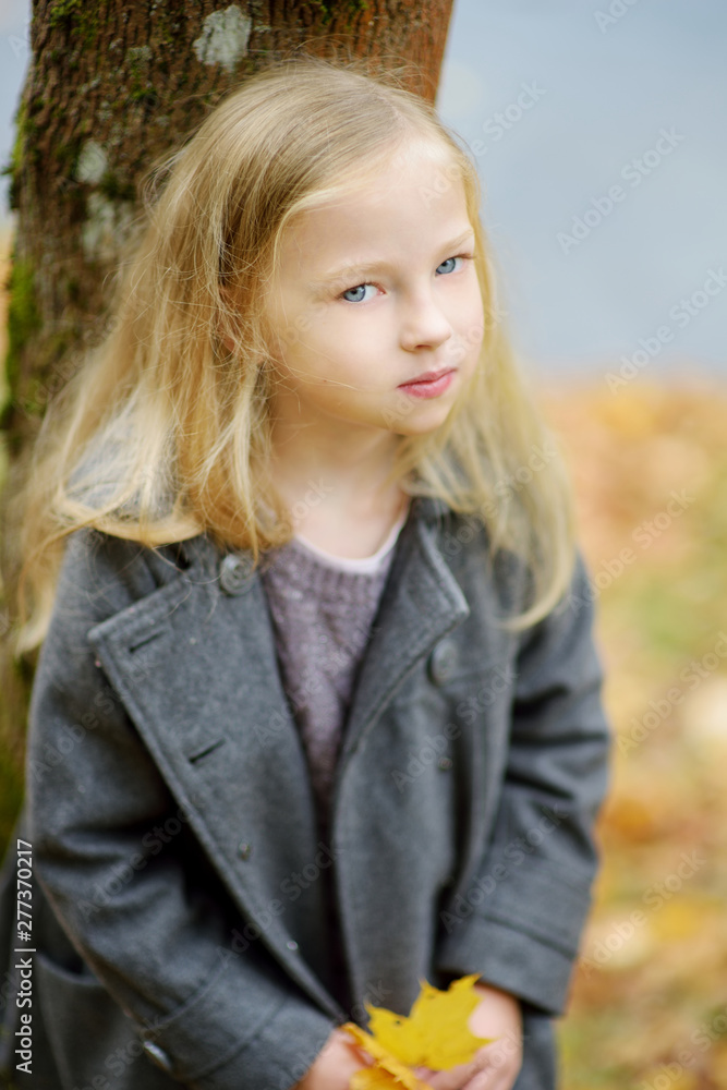 Adorable young girl having fun on beautiful autumn day. Happy child playing in autumn park. Kid gathering yellow fall foliage. Adorable young girl having fun on beautiful autumn day. Happy child playing in autumn park. Kid gathering yellow fall foliage.
