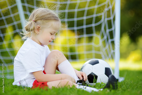 Cute little soccer player having fun playing a soccer game on sunny summer day. Sport activities for children.