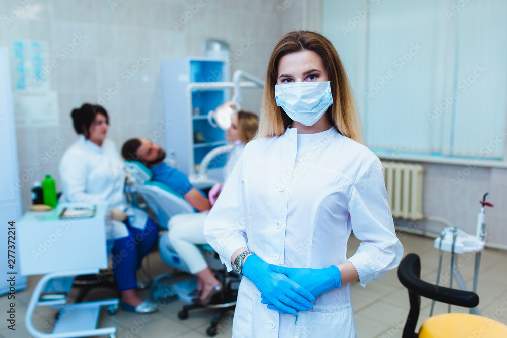 Dental clinic. Portrait of a professional dentist on the background of a working team of doctors. Concept of medical education and medical insurance Dental clinic. Portrait of a professional dentist on the background of a working team of doctors. Concept of medical education and medical insurance