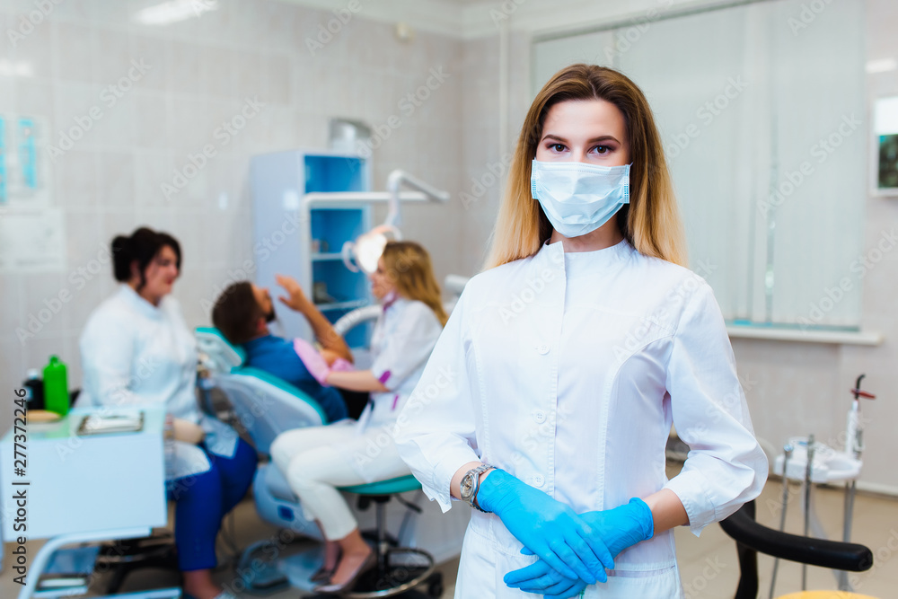 Dental clinic. Portrait of a professional dentist on the background of a working team of doctors. Concept of medical education and medical insurance Dental clinic. Portrait of a professional dentist on the background of a working team of doctors. Concept of medical education and medical insurance