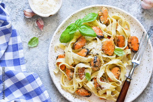 Tagliatella pasta with mussels and cream sauce on the kitchen table. View from above.