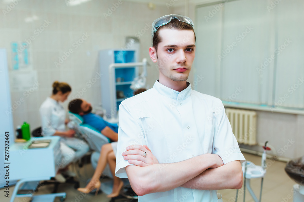 Fototapeta premium Dental clinic. Portrait of a professional dentist on the background of a working team of doctors. Concept of medical education and medical insurance