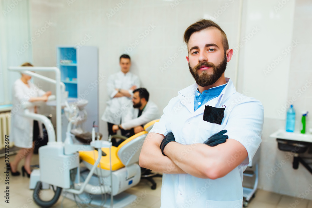 Dental clinic. Portrait of a professional dentist on the background of a working team of doctors. Concept of medical education and medical insurance Dental clinic. Portrait of a professional dentist on the background of a working team of doctors. Concept of medical education and medical insurance