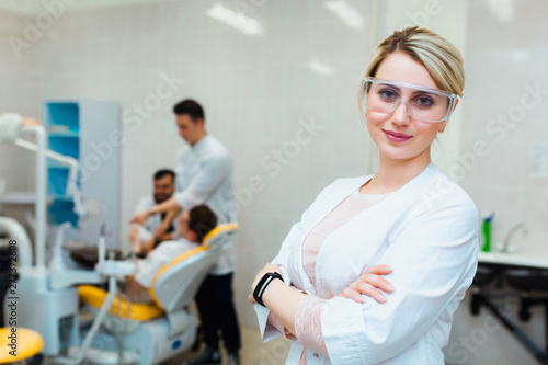 Dental clinic. Portrait of a professional dentist on the background of a working team of doctors. Concept of medical education and medical insurance