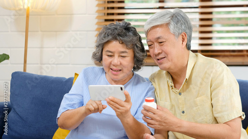Senior asian couple holding bottle of pill make video conference call to doctor  pharmacy consulting about pill for medical health care of old  retirement  elderly people