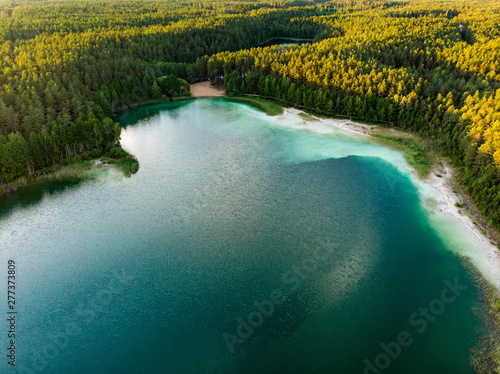Aerial view of beautiful green waters of lake Gela. Birds eye view of scenic emerald lake surrounded by pine forests.