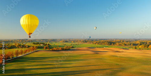 Colorful hot air balloon flying over forests surrounding Vilnius city on sunny autumn evening. photo