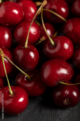 close up view of red delicious shiny cherries on wooden table