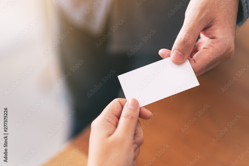 Two businessman holding and exchanging empty business card - obrazy, fototapety, plakaty 