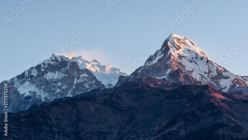 Poonhill view of Annapurnas. Warm pink and orange sunrise light over Annapurna mountain range with blue sky and beautiful clouds  view from Poon hill in Himalayas  Nepal. Annapurna one and Annapurna s