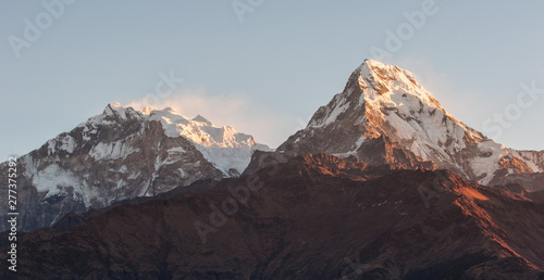 Poonhill view of Annapurnas. Warm pink and orange sunrise light over Annapurna mountain range with blue sky and beautiful clouds, view from Poon hill in Himalayas, Nepal. Annapurna one and Annapurna s