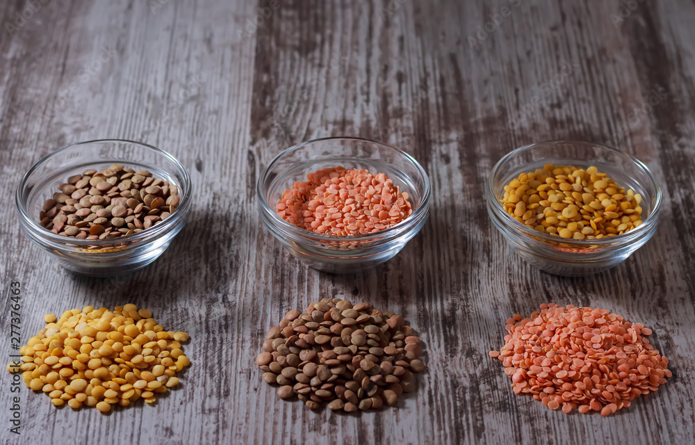 Green, red and yellow lentils in small glass bowls on wooden background. Indian kitchen Green, red and yellow lentils in small glass bowls on wooden background. Indian kitchen