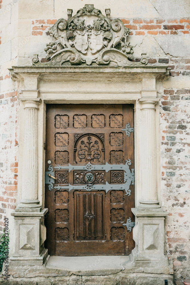 Naklejka premium Medieval beautiful antique wooden door and brick wall