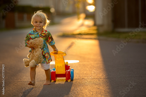 Beautiful toddler child, playing with plastic toys, blocks, cars on sunset