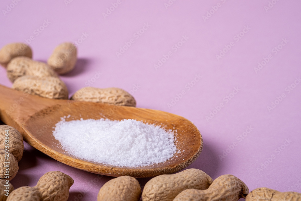 Peanuts and wooden spatula with salt minimal on purple background backdrop food nut texture copy space angle view Peanuts and wooden spatula with salt minimal on purple background backdrop food nut texture copy space angle view