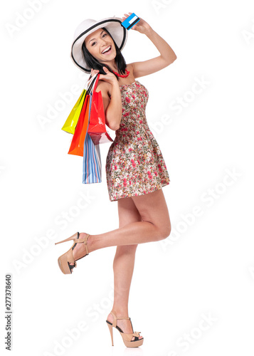 Full length portrait of young happy smiling woman holding a credit card or gift card and shopping bags, isolated on white background
