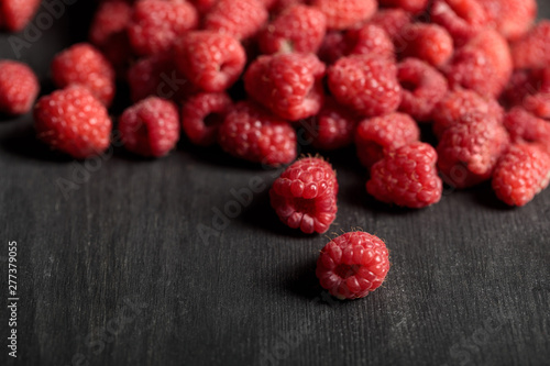 selective focus of tasty ripe raspberries scattered on wooden table