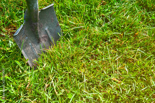 garden tools shovel stuck in the ground on the green grass top side view