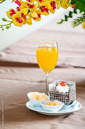 Orange juice in champagne glass with cake and bagery beside. photo