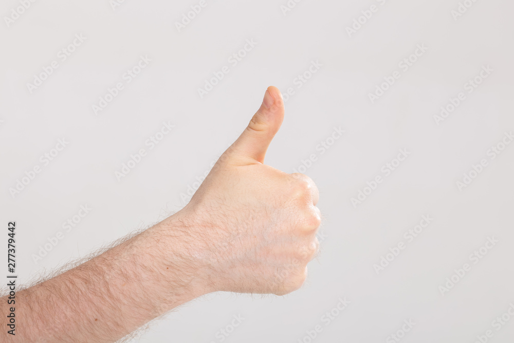 Closeup of male hand showing thumbs up over white background with copy space Closeup of male hand showing thumbs up over white background with copy space