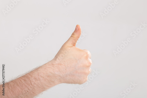 Closeup of male hand showing thumbs up over white background with copy space © satura_