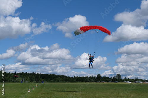 Skydiving. A pretty girl is landing on the field.