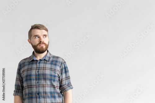 Young man with a mustache and beard making bulging eyes in surprise against a white background with copy space. Concept of surprise and uncertainty.