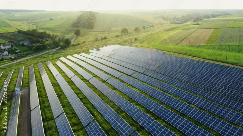 Flying over a solar farm with photovoltaic panels converting solar power to electricity for green energy on agricultural land