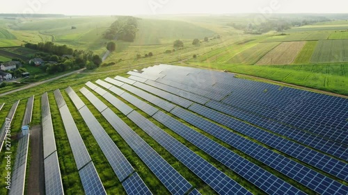 Flying over a solar farm with photovoltaic panels converting solar power to electricity for green energy on agricultural land