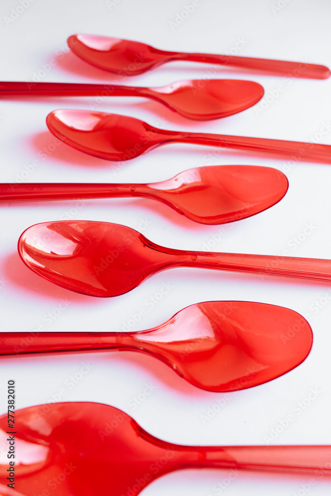 Red plastic spoons flat lay on white background Red plastic spoons flat lay on white background