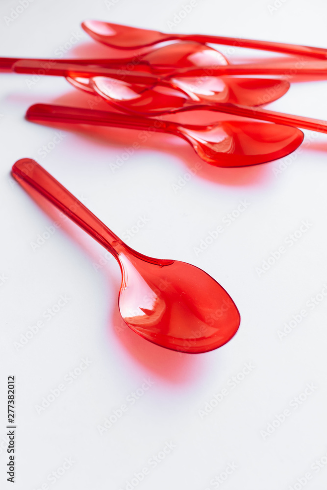 Red plastic spoons flat lay on white background Red plastic spoons flat lay on white background